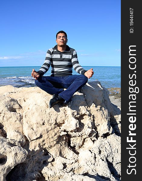 Arab man meditating sitting on rocks at the coast of tunisia. Arab man meditating sitting on rocks at the coast of tunisia.