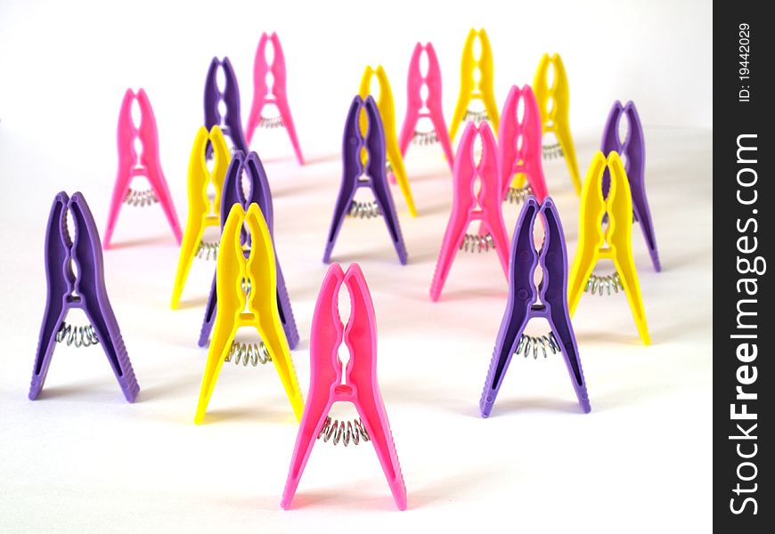 Bright clothes pegs standing on white background