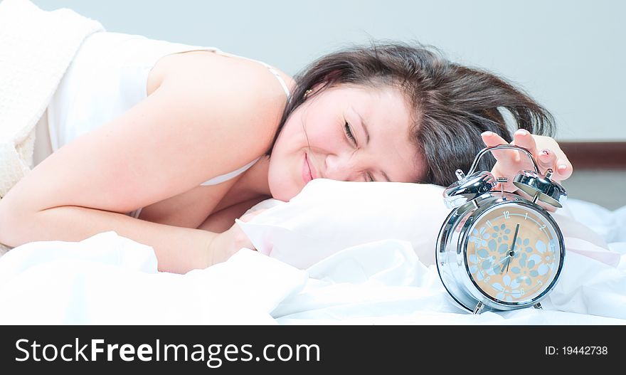 The girl tries to ungear an alarm clock at bedroom