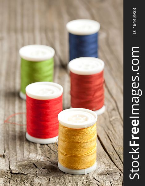 Spools of colorful threads on old wooden table