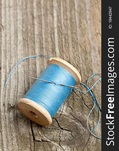 Top view on spool of blue thread and needle on old wooden table. Top view on spool of blue thread and needle on old wooden table