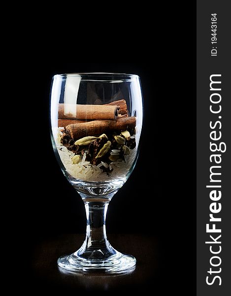 Star anise and rice with cinnamon sticks in wine glass isolaed black background