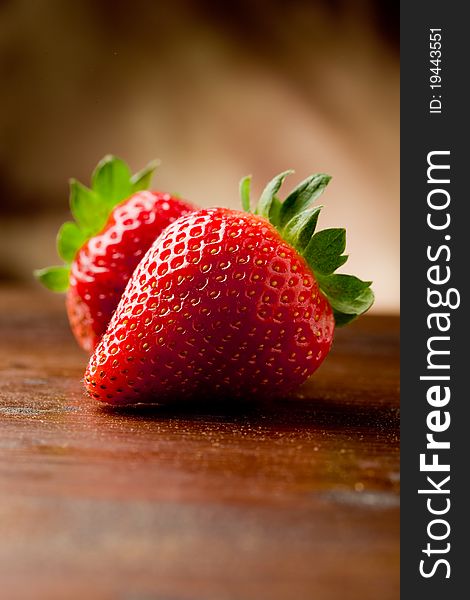 Photo of delicious strawberries on wooden table in front of brown rustical background