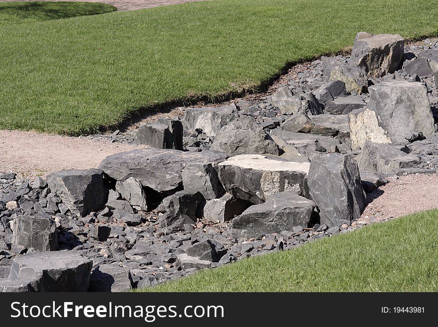 Stony channel of a dried-up stream between green lawns. Stony channel of a dried-up stream between green lawns.