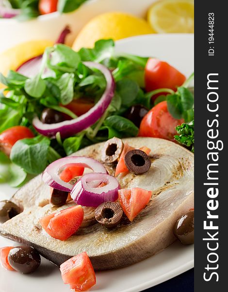 Grilled swordfish with mixed salad on white towel in front of blue background