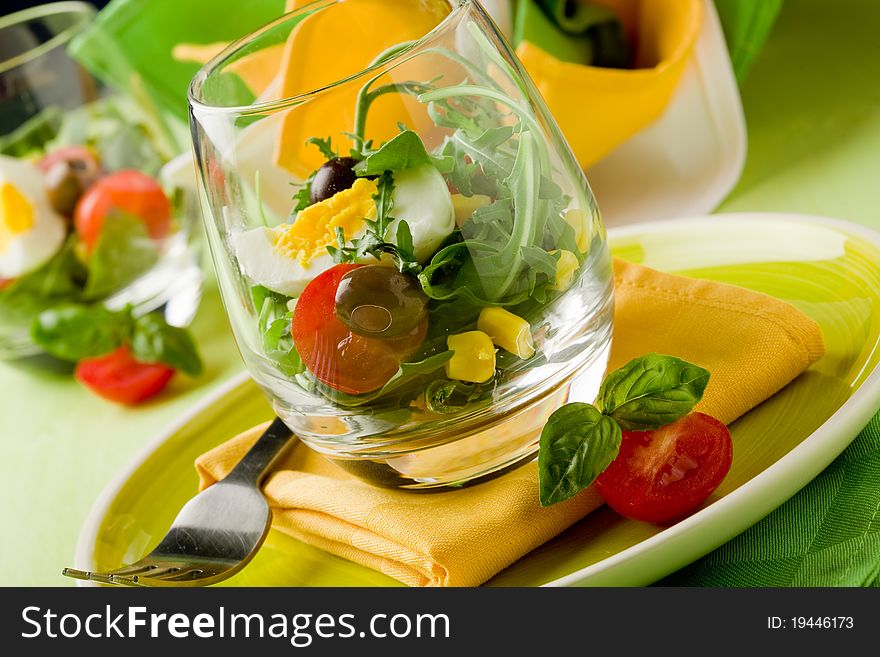 Delicious starter of mixed salad inside a glass on green wooden table