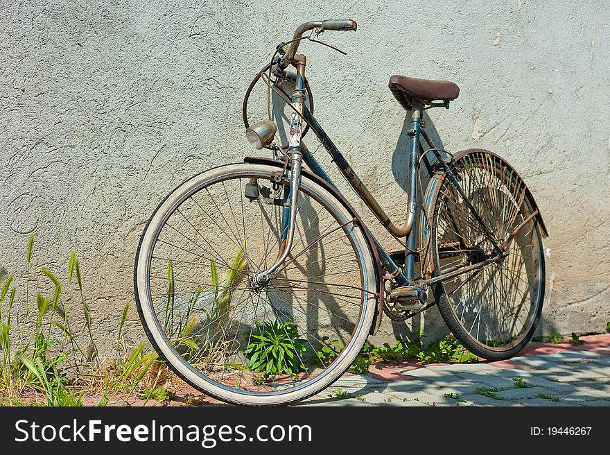 A woman bicycle was leaning against the wall during a sunny day. A woman bicycle was leaning against the wall during a sunny day