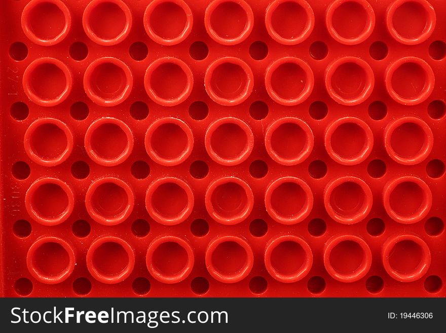 Closeup of a toy part showing circles on red plastic.