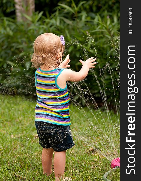 Little girl playing with a garden hose. Little girl playing with a garden hose