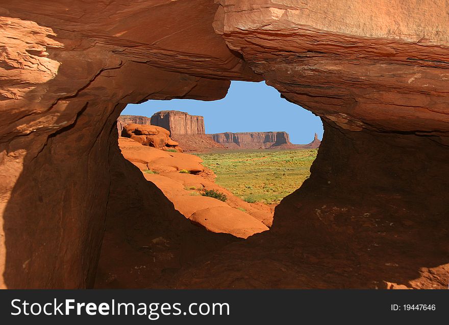 Early morning view of Monument Valley framed by opening in rock formation - Arizona. Early morning view of Monument Valley framed by opening in rock formation - Arizona