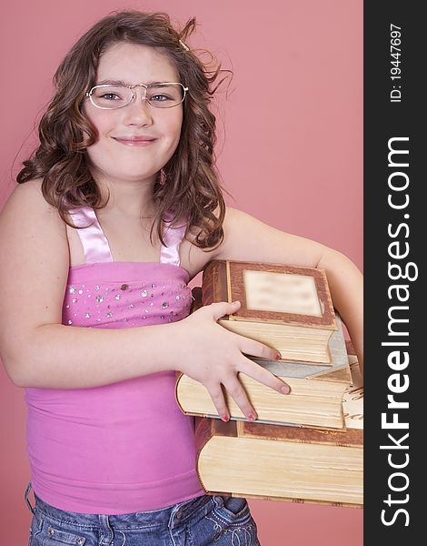 Young school aged girl wearing glasses and carrying lots of books. Young school aged girl wearing glasses and carrying lots of books.