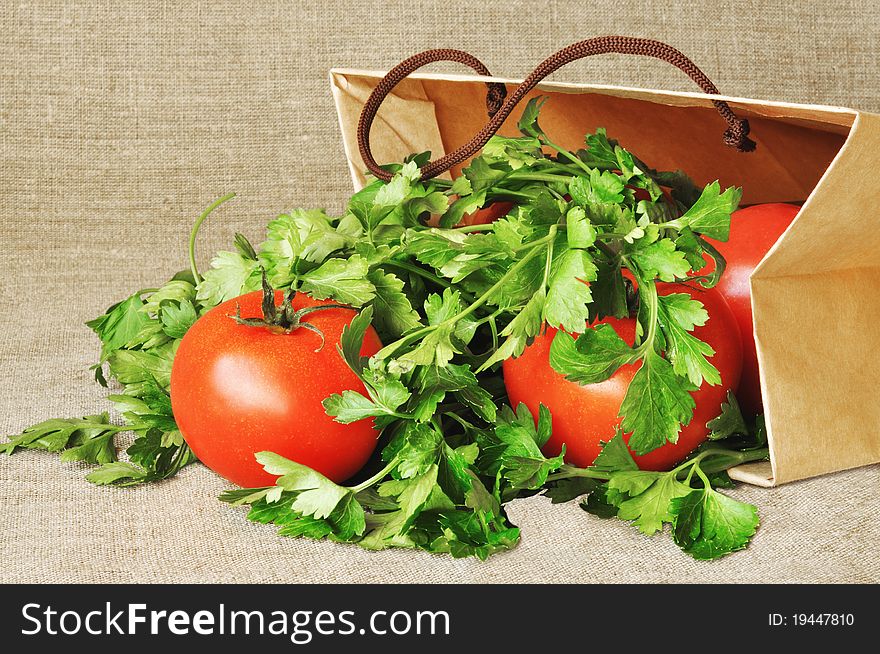 Tomatoes and parsley in a paper package on  against from a sacking