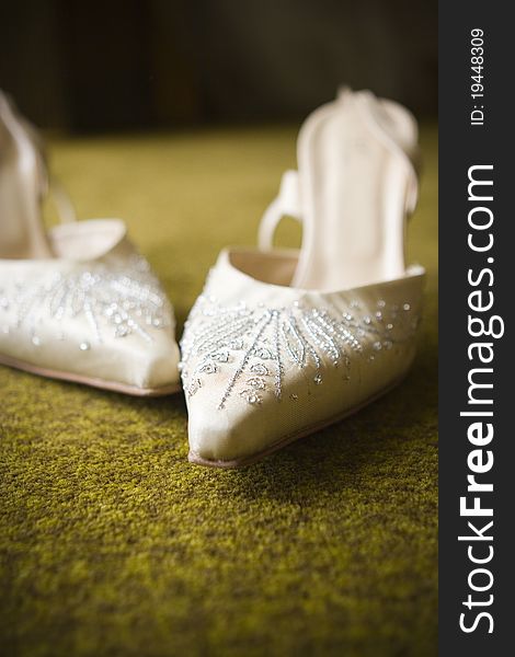 A close up of white beaded wedding shoes