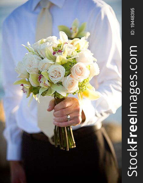 A groom holding the bride's wedding bouquet