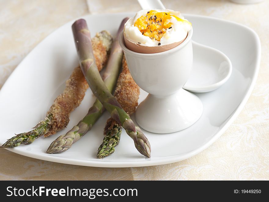 Soft boiled egg with asparagus soldiers on a plate