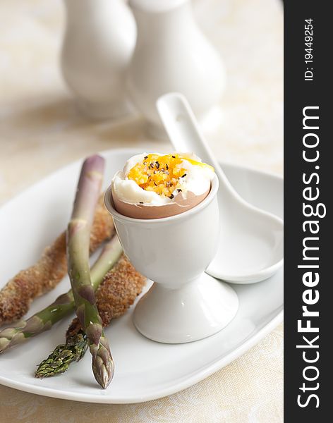 Soft boiled egg with asparagus soldiers on a plate