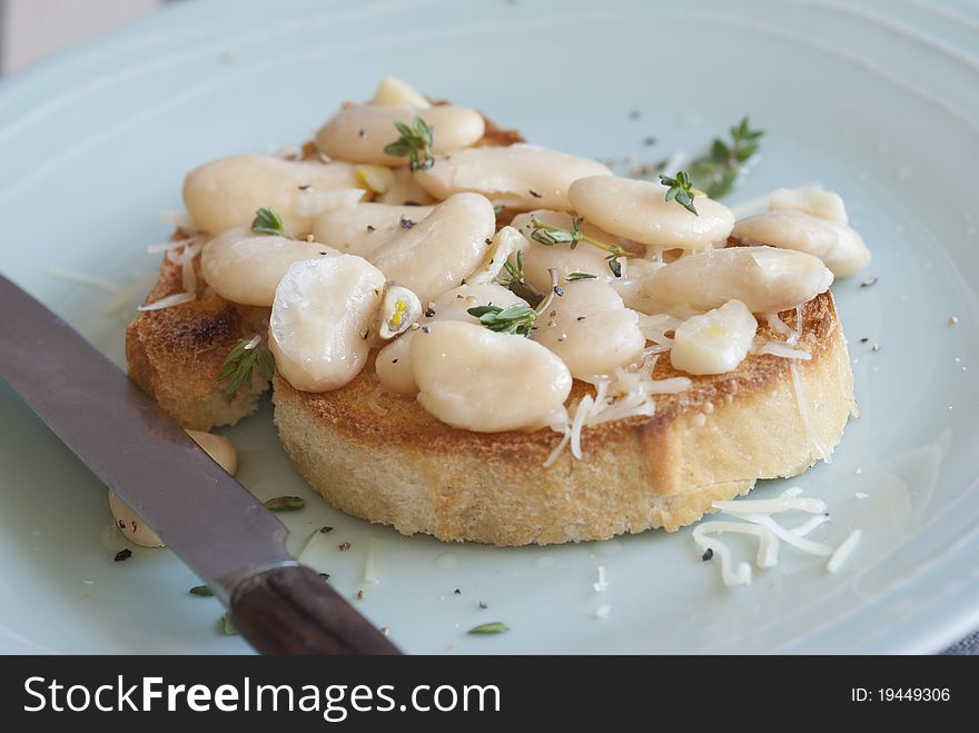 Toasted bread topped with butterbeans and thyme on a plate