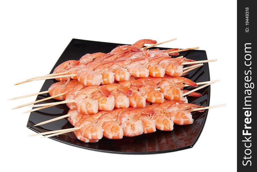 Skewers of shrimp on a black plate, isolated on a white background