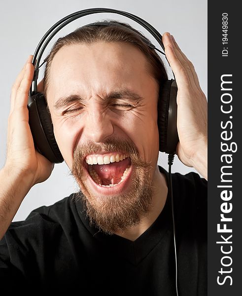 Young man in headphones and screaming loudly. Young man in headphones and screaming loudly
