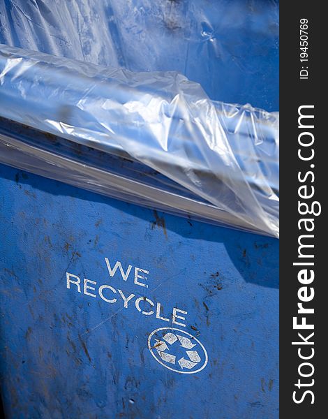 Blue recycling container with the words WE RECYCLE and the recycle logo printed on the side. Blue recycling container with the words WE RECYCLE and the recycle logo printed on the side.