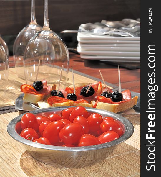 Table in preparation for an cocktail with cherry tomatoes in the foreground. Table in preparation for an cocktail with cherry tomatoes in the foreground