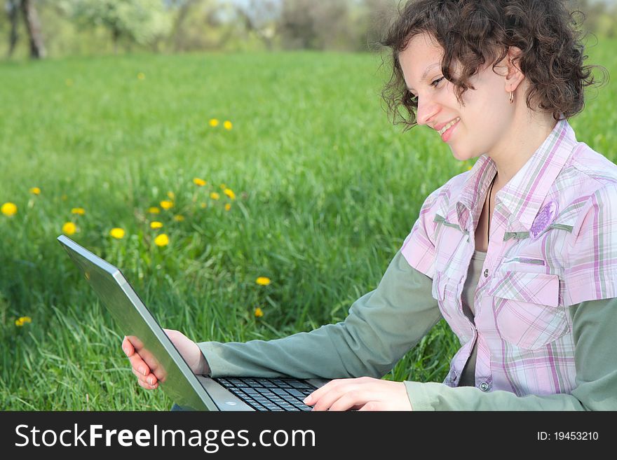 Girl with  laptop on the spring meadow