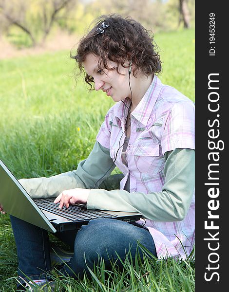 Girl with a laptop on the spring meadow