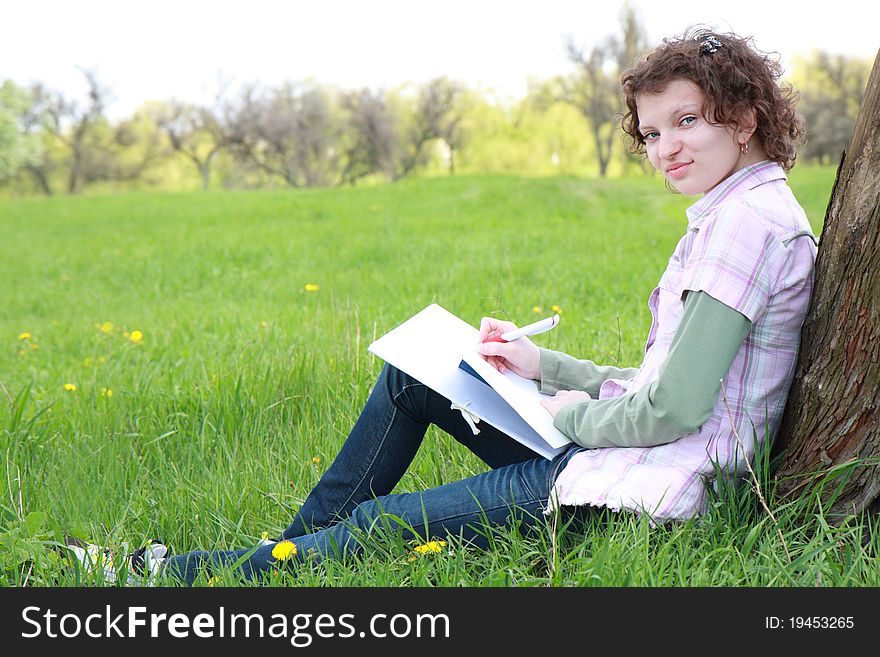 Girl student in park writes in writing book