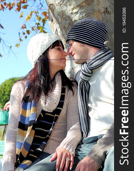 Young couple looking at each other on a park bench in winter clothes