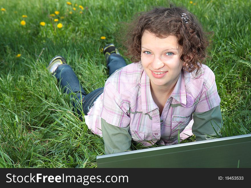 Girl with  laptop on the spring meadow