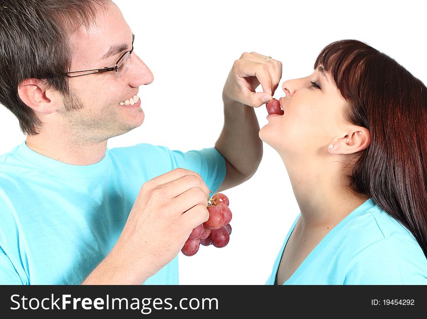 Man feeding woman grapes on a white background