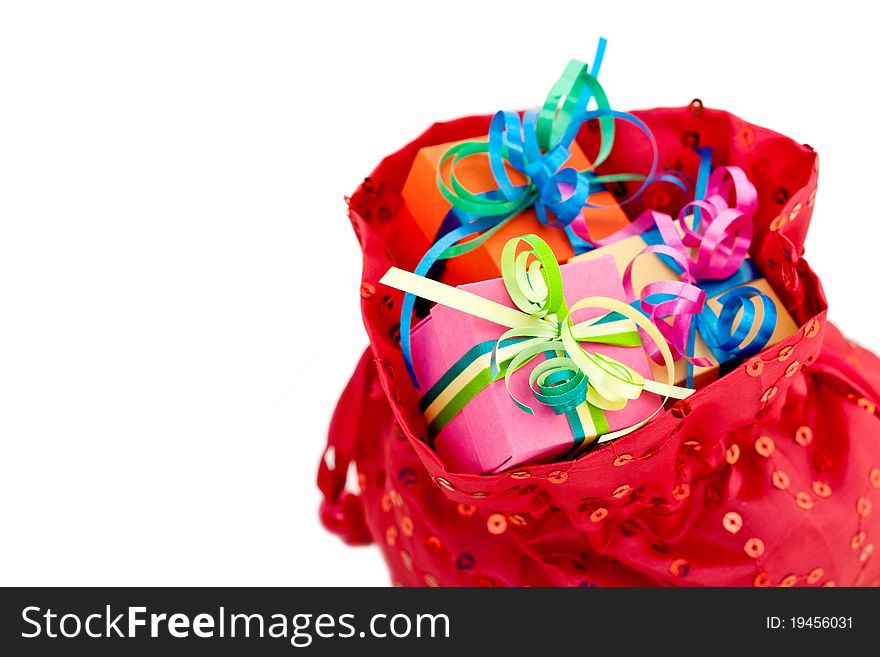 Colorful gift boxes with ribbons and bows in a red bag, isolated on white studio background. Colorful gift boxes with ribbons and bows in a red bag, isolated on white studio background