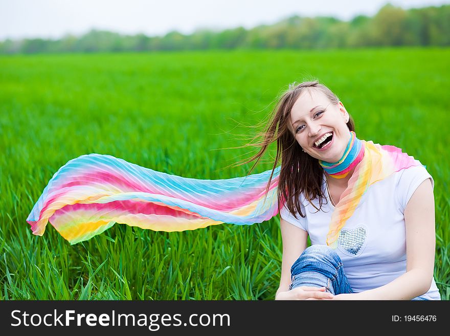 Smiley girl in a multicolored crarf on a grass. Smiley girl in a multicolored crarf on a grass