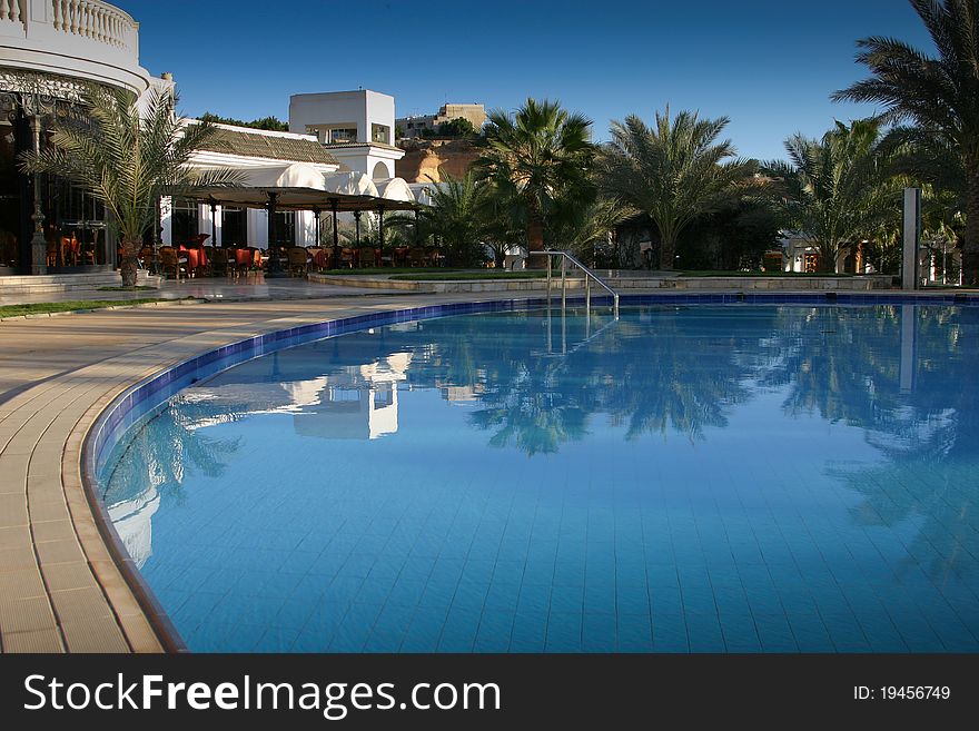 The pool with the Blue water, palms and the blue sky. The pool with the Blue water, palms and the blue sky