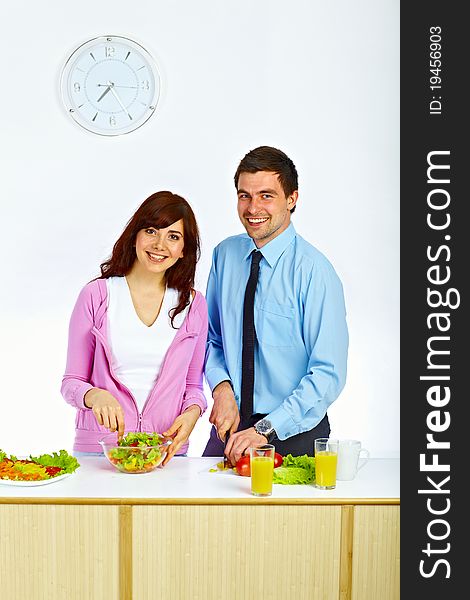 Beautiful couple preparing a salad for lunch in the kitchen