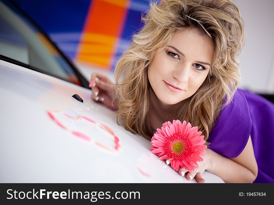 Young woman on hood of New car with flower and petals