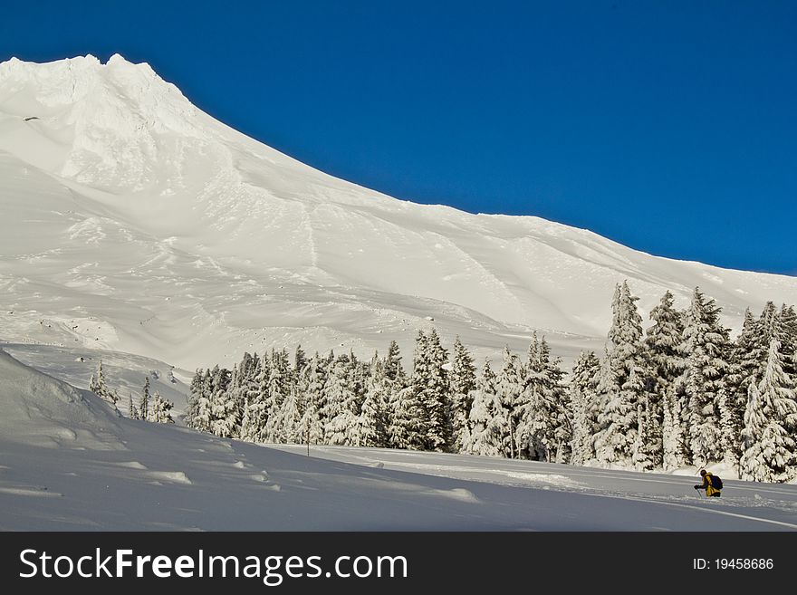 A Shot of Mount Hood in Oregon with a hiker walking the slope. A Shot of Mount Hood in Oregon with a hiker walking the slope