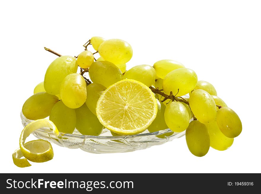 Grapes and lemon in a glass vase on the white isolated background. Grapes and lemon in a glass vase on the white isolated background