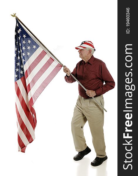 A happy senior patriot wearing a stars and stripes hat while carrying a large American flag. Isolated on white. A happy senior patriot wearing a stars and stripes hat while carrying a large American flag. Isolated on white.