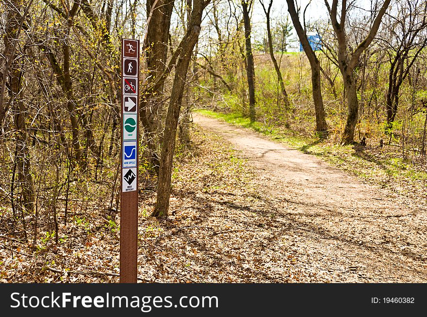 A Biking, Walking, and Hiking sign at the start of a Trail in the woods. A Biking, Walking, and Hiking sign at the start of a Trail in the woods