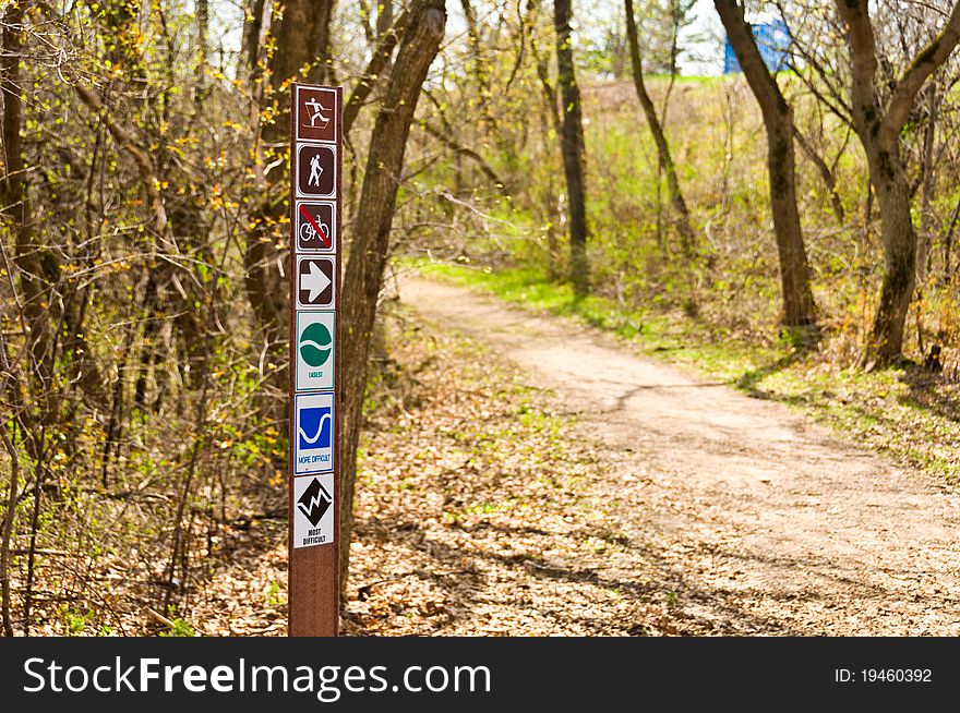 A Biking, Walking, and Hiking sign at the start of a Trail in the woods. A Biking, Walking, and Hiking sign at the start of a Trail in the woods