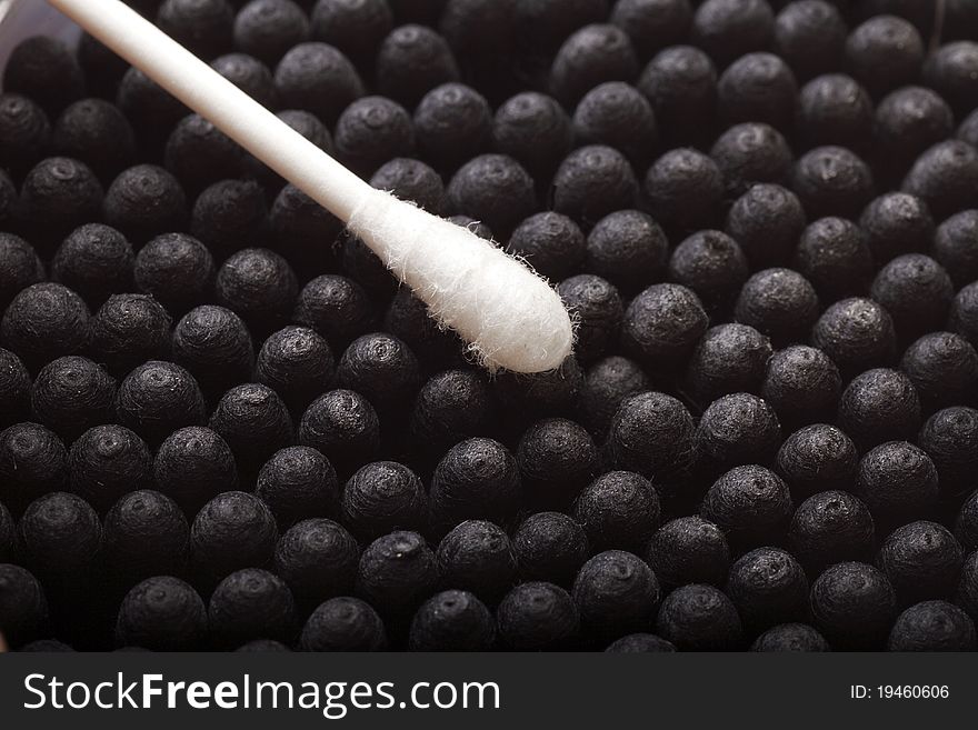 Close-up of a white cotton swab on dark cotton swabs background.