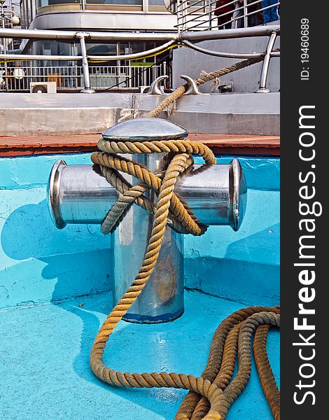 Metal bollard with thick rope at a ship deck. Metal bollard with thick rope at a ship deck