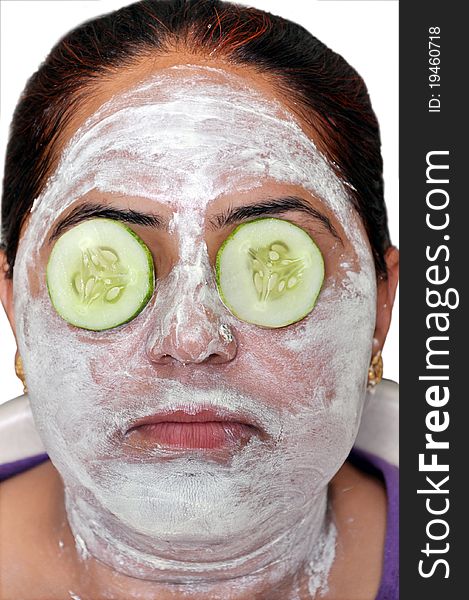 Lady applying a green cucumber face pack on his face.she is keeping cucumber slices on his eyes.it is good for face. Lady applying a green cucumber face pack on his face.she is keeping cucumber slices on his eyes.it is good for face.