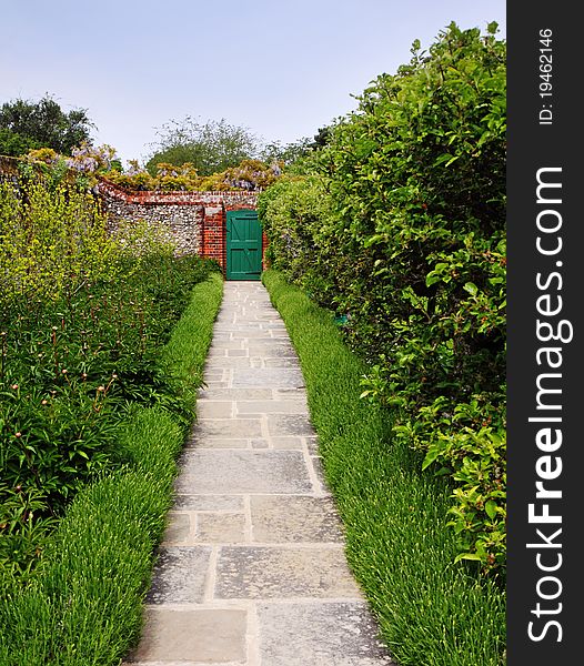 An english Walled garden with path between Flowerbeds leading to a door in the wall. An english Walled garden with path between Flowerbeds leading to a door in the wall