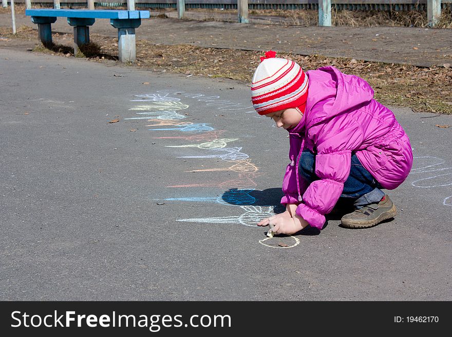Girl drawing on the asphalt.
