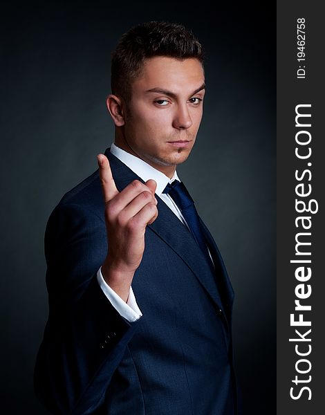 Portrait of handsome stylish man in elegant suit pointing the finger