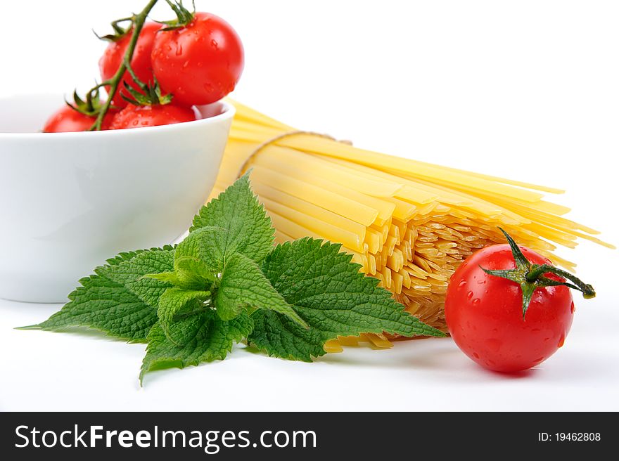 Raw yellow pasta, tomatoes and green leaves. Raw yellow pasta, tomatoes and green leaves