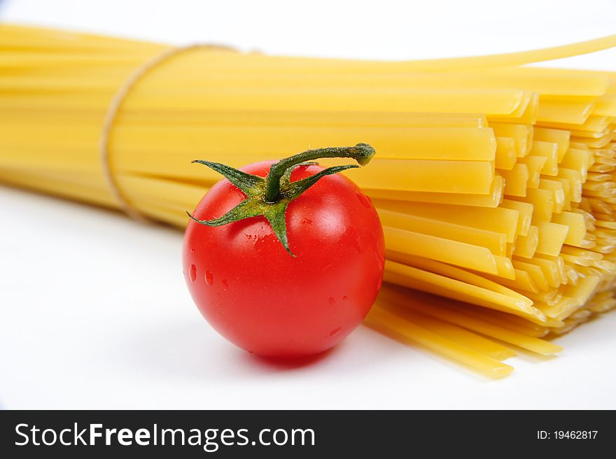 Raw yellow pasta and a red tomato. Raw yellow pasta and a red tomato