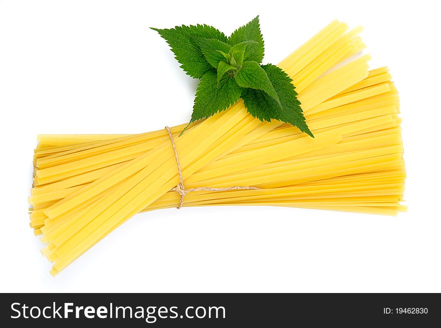 An image of raw yellow pasta and green plant. An image of raw yellow pasta and green plant